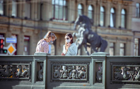 Russia, Saint Petersburg, may 30, 2020: two girls in medical masks on the famous Anichkov Bridge in the city center on a walkのeditorial素材