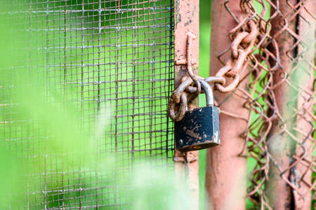 The lock on a chain hangs on the gateの写真素材