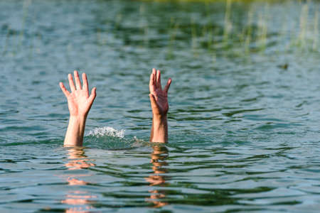 Hands stick out of the water to represent a drowning personの写真素材
