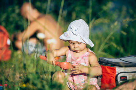 Russia, Saint Petersburg, June 24, 2020: a Little girl in a pink dress plays in the sand on the shore of a lakeのeditorial素材