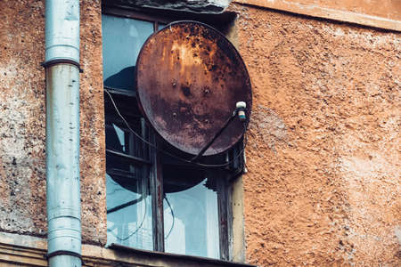 Russia Petersburg August 4, 2020: Rusty satellite dish antenna on the facade of an old building.のeditorial素材