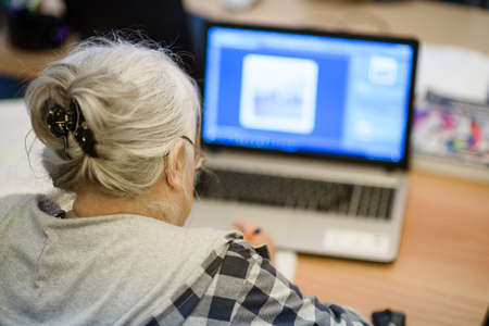 An elderly woman in a class at a leisure center is studying computer workの写真素材