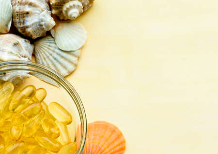 Golden fish oil capsules on a yellow background - the concept of health and natural marine vitamins.の写真素材
