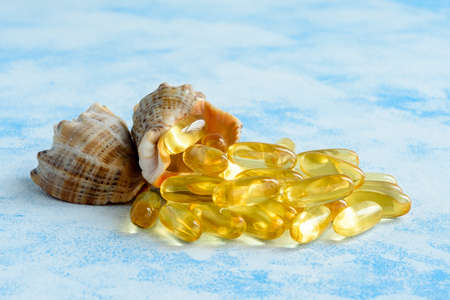 Golden fish oil capsules on a blue background - the concept of health and natural marine vitamins.