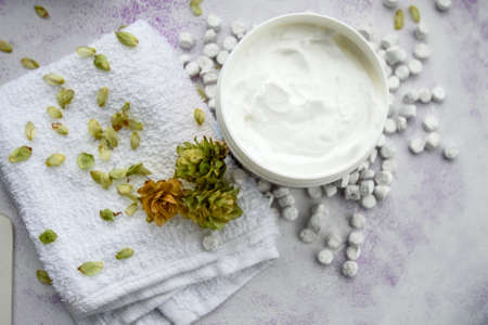 Close-up of a smooth moisturizer in a plastic jar on a blue background with white small stones on top. The concept of skin care.の写真素材