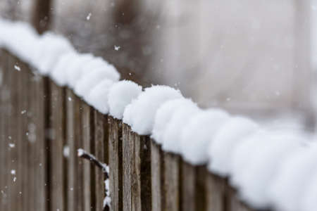 Falling snow on the background of an old wooden fence - a rustic winter landscapeの写真素材