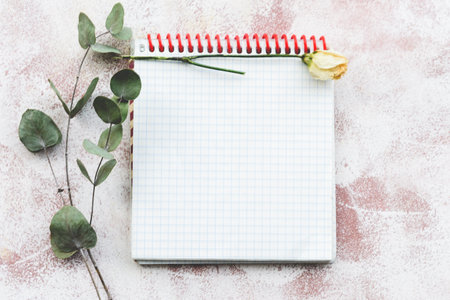 Stationery romantic delicate background-a clean notebook, a sprig of eucalyptus and yellow roses. Top view, close-up, and copy space.の写真素材