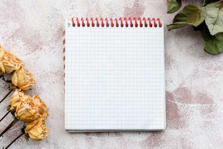 Stationery delicate background-a clean notebook and yellow roses. Top view, close-up, and copy space.の写真素材