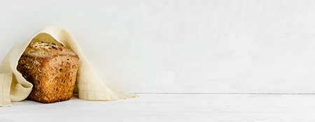 banner with a white wall background and copy space - Homemade grain bread and a linen napkin. Home kitchen cooking decor.の写真素材