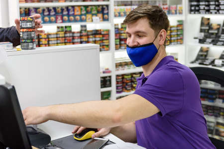 Russia Russia, St. Petersburg, May 15, 2021: A salesman in a medical mask in a tobacco store behind the counter serves a customer. Trade and business. Shop during the pandemicのeditorial素材