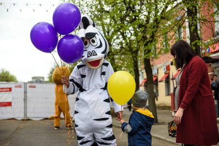 Russia, Gatchina, May 15, 2021: A man in a zebra costume on a city street greets passers-by and...