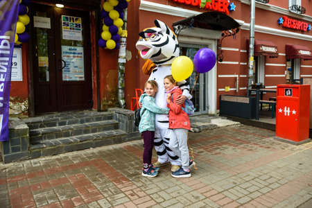 Russia, Gatchina, May 15, 2021: A man in zebra costume on a city street embraces and takes photos with passers-by. Advertising on the street. Work in advertising.のeditorial素材