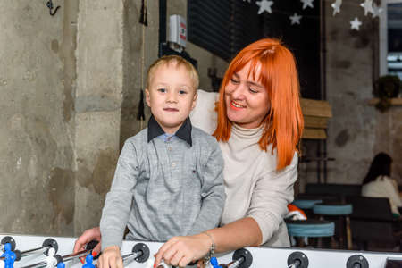 Russia, Gatchina, November 20212: A young mother and child play table hockey in a cafeのeditorial素材