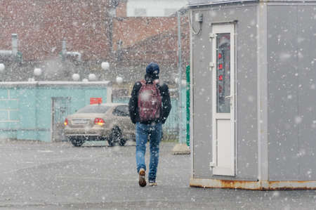 Russia, St. Petersburg, December 2021: A young man with a backpack on his back walks through a...