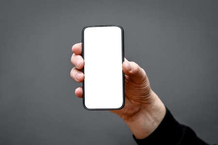 smartphone frame with an empty white screen on a dark background in a man's hand.