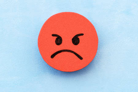 red angry face on a blue background. The concept of negative mood. customer dissatisfaction.の写真素材