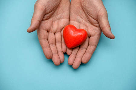 Red heart in hand on a blue background top view. The concept of health, donation and charity.の写真素材
