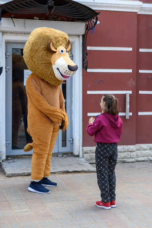 Russia, Gatchina, May 15, 2022: An animator in a lion costume communicates with a child in the cityのeditorial素材