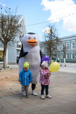 Russia, Gatchina, May 15, 2022: Animator in a penguin costume on a city street. Advertising on the street. Work in advertising.のeditorial素材