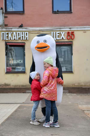 Russia, Gatchina, May 15, 2022: An animator in a penguin costume and children on a city street from the cartoon Madagascarのeditorial素材