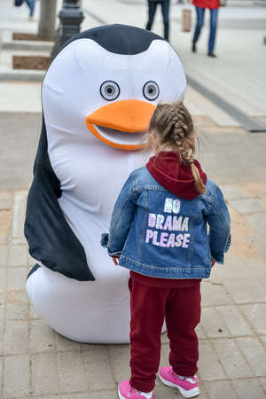 Russia, Gatchina, May 15, 2022: An animator in a penguin costume and children on a city street from the cartoon Madagascarのeditorial素材
