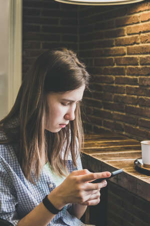 A girl in the cafeteria with a phoneの写真素材