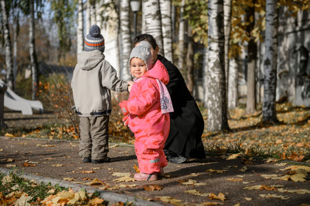A young mother with a little daughter and son on a walkの写真素材