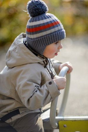 A three-year-old boy rides a swing on the playgroundの写真素材