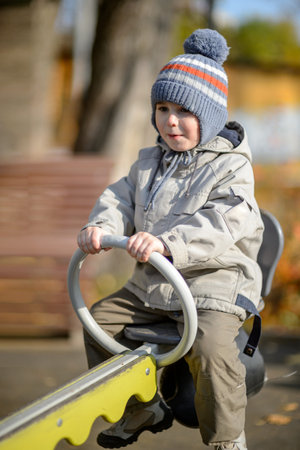 A three-year-old boy rides a swing on the playgroundの写真素材