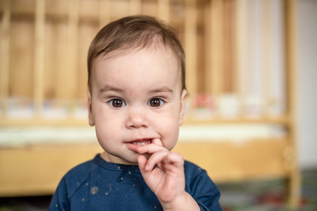 a little girl holds her fingers in her mouthの写真素材