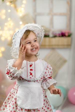 A little beautiful girl in a doll dress and a hatの写真素材