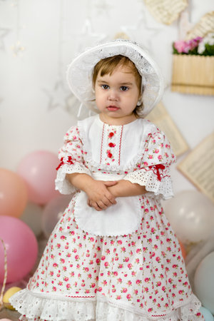 A little beautiful girl in a doll dress and a hatの写真素材