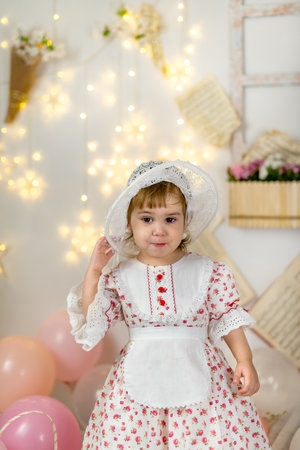 A little beautiful girl in a doll dress and a hatの写真素材