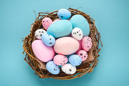 Eggs painted blue and pink on a blue background in a nest basket on a blue backgroundの写真素材