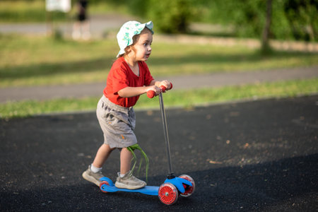 Cute little girl riding scooter on the road in the parkの写真素材