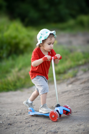 Little girl child riding a scooter aloneの写真素材