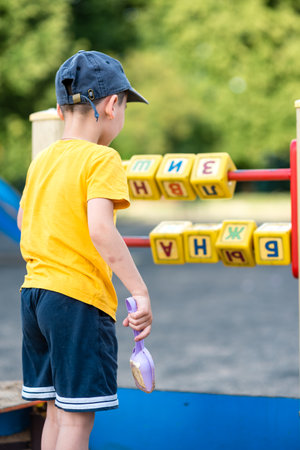 Little boy playing with cubes and letters on playground close upの写真素材