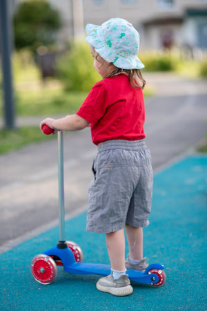Little girl riding a scooter alone on a playground in summerの写真素材