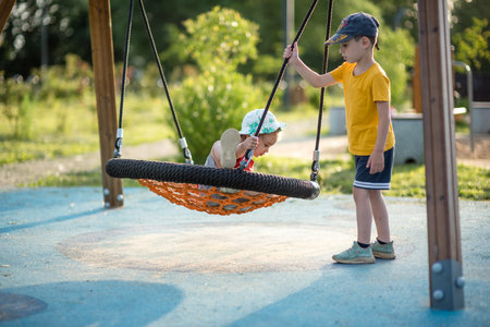 Cute little boy swinging on a swing in the park in summerの写真素材
