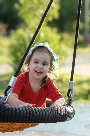 Adorable little girl having fun on a swing in the park.の写真素材