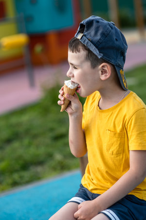 Little boy child eating ice cream in summer on playgroundの写真素材