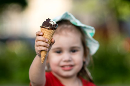 Little girl holding ice cream in hand - focus on ice cream and blurred backgroundの写真素材