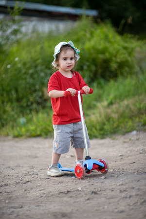 Little girl child riding a scooter aloneの写真素材