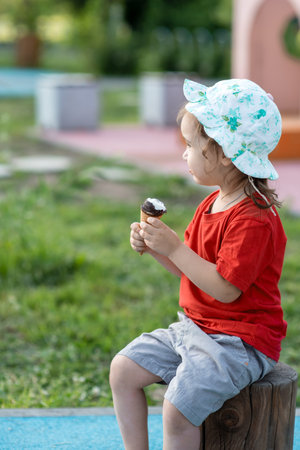 Little girl child eating ice cream in summer on playgroundの写真素材