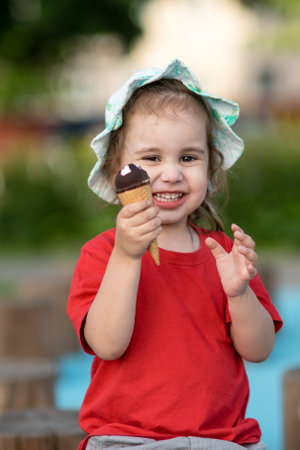 Little girl holding ice cream in hand in summer on playgroundの写真素材