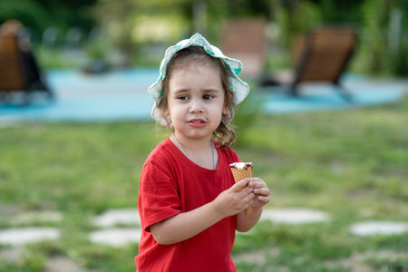 Little girl eating ice cream in the park in summer. Close-up portrait of a childの写真素材