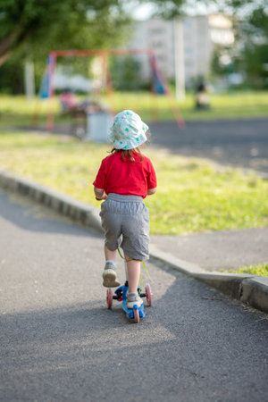 Little girl on a scooter alone in a park in summerの写真素材