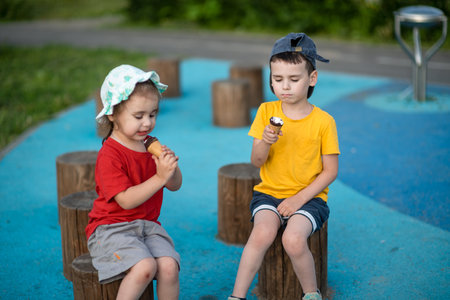 Two children eating ice cream in the park. Selective focus.の写真素材