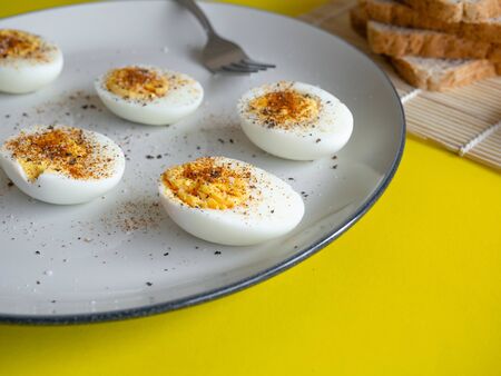 Boiled egg topped with Cayenne pepper Pepper and Salt on a white dish, Egg colors white and yellowの写真素材