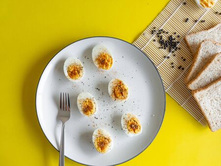 Boiled egg topped with Cayenne pepper Pepper and Salt on a white dish, Egg colors white and yellow, Eat with breadの写真素材